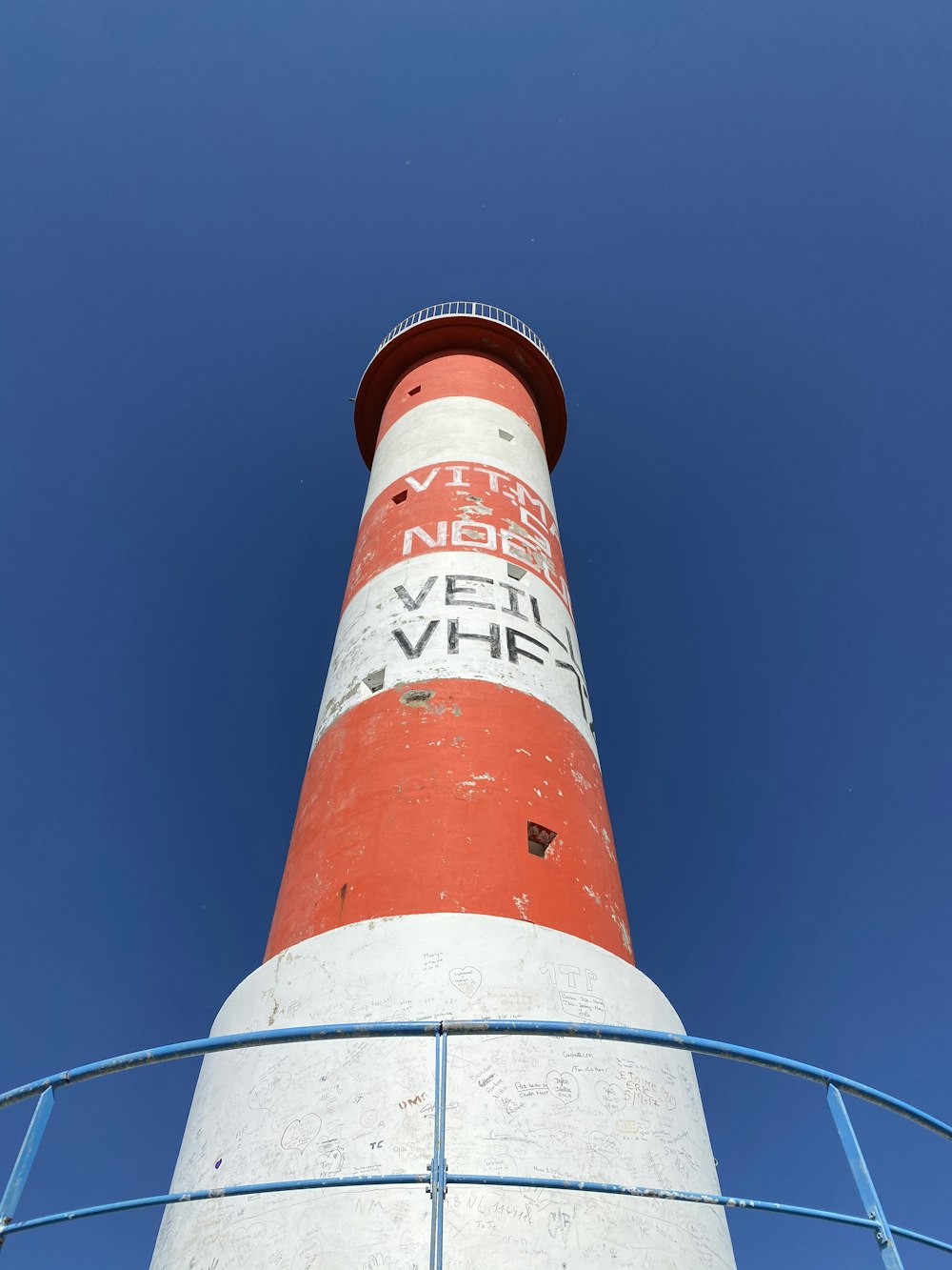 torre di cemento rossa e bianca sotto il cielo blu durante il giorno