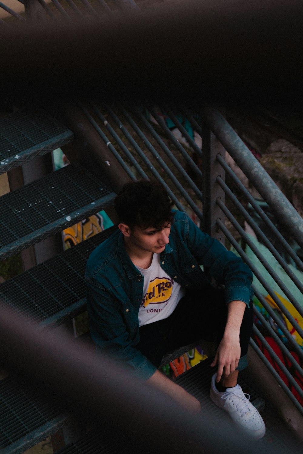 man in blue and white hoodie and blue denim jeans sitting on stairs