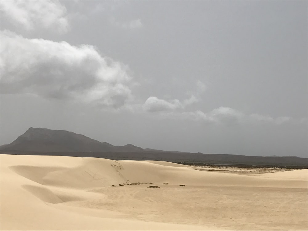 brown sand under white clouds during daytime