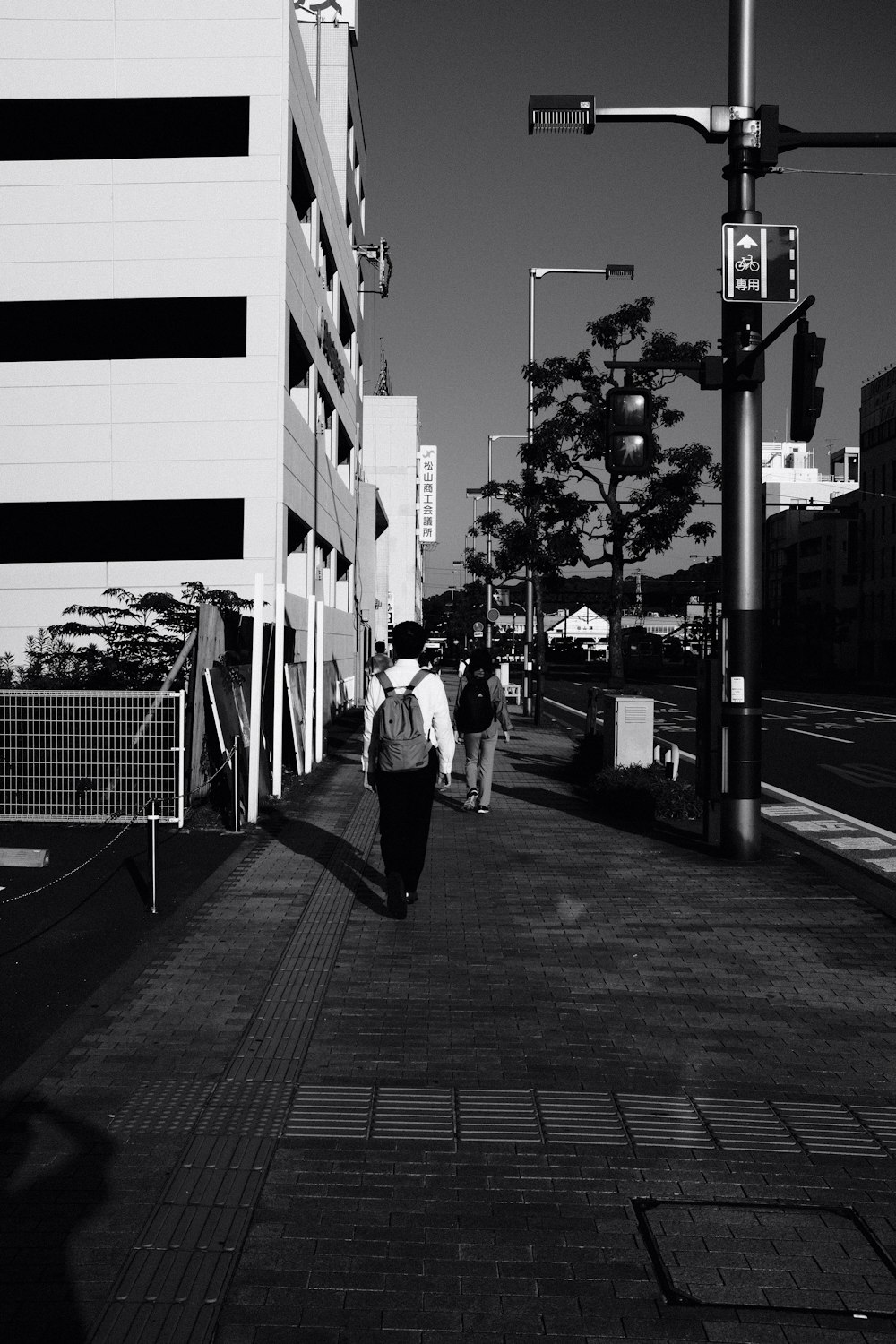 grayscale photo of man and woman walking on sidewalk