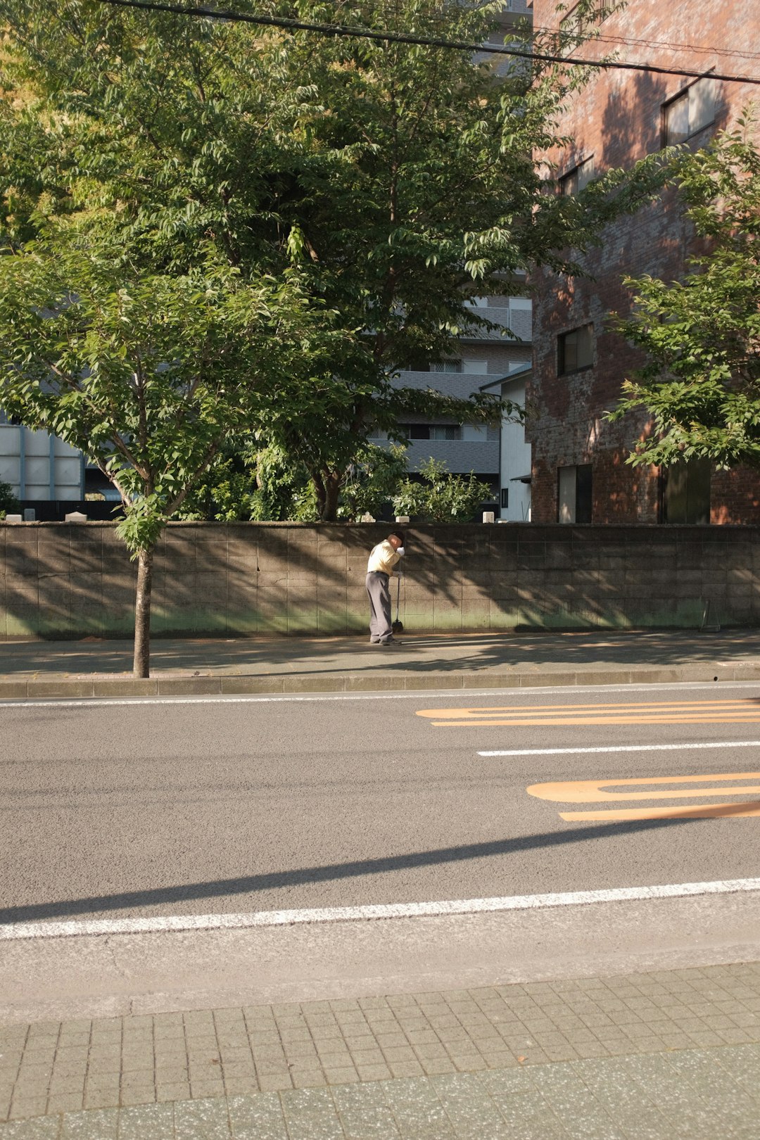 man in white t-shirt and gray pants walking on gray concrete road during daytime
