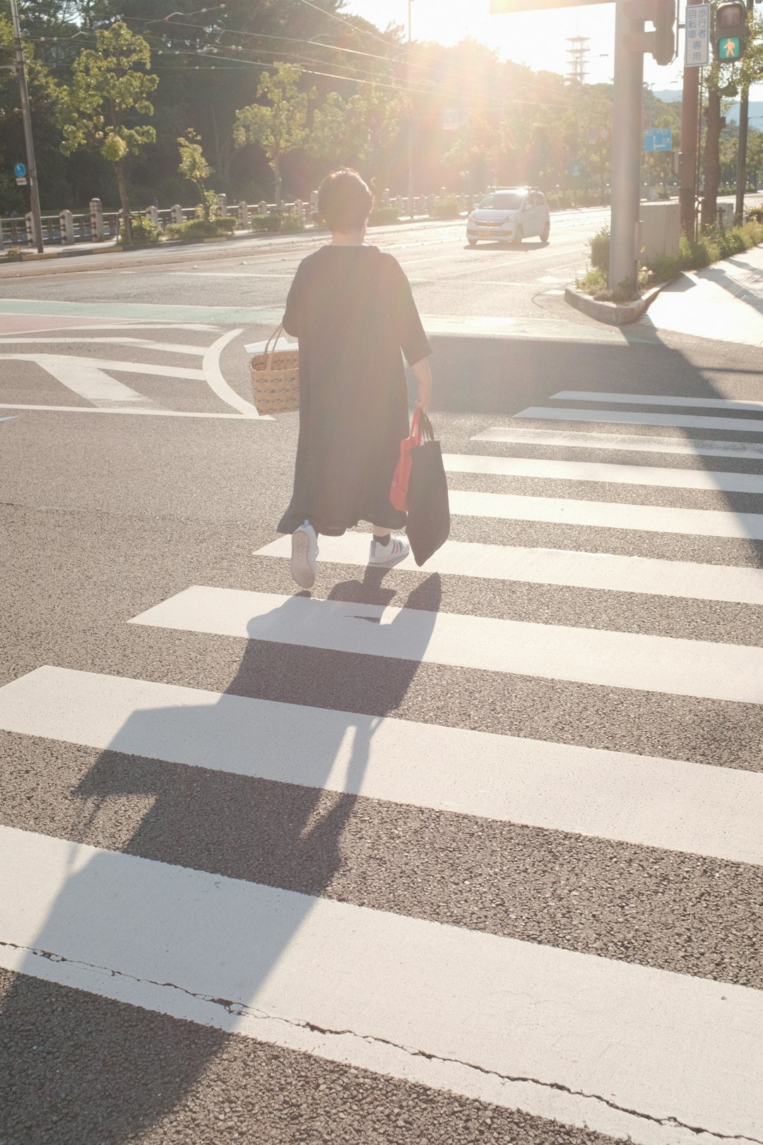 person in black long sleeve shirt and black pants walking on pedestrian lane during daytime