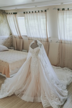 A delicate lace wedding dress draped elegantly on a vintage mannequin bathed in soft natural light.