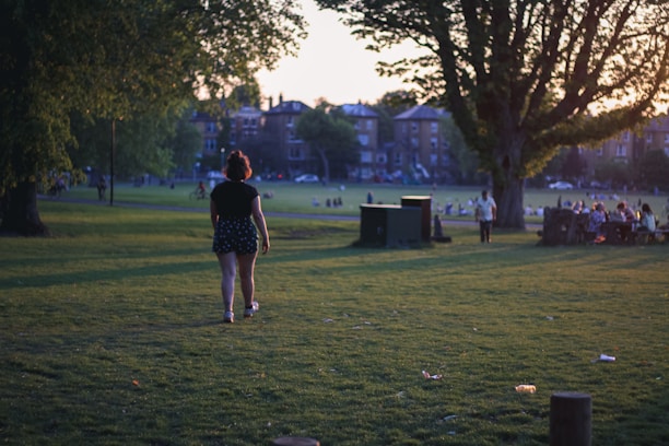 A man confidently walking through a city park during sunset, symbolizing personal growth.