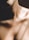 Close-up of hands gently massaging a person’s shoulder with soft lighting.
