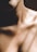 Close-up of hands gently massaging a person’s shoulder with soft lighting.