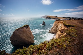 brown rock formation on sea under blue sky during daytime