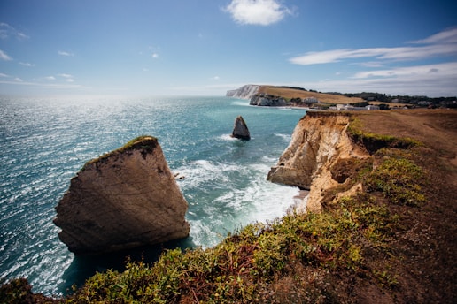 brown rock formation on sea under blue sky during daytime