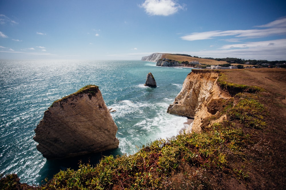 brown rock formation on sea under blue sky during daytime