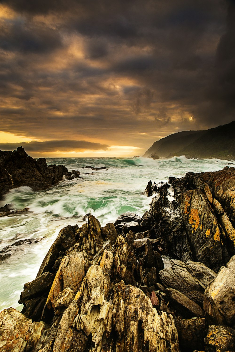 ocean waves crashing on rocky shore during sunset