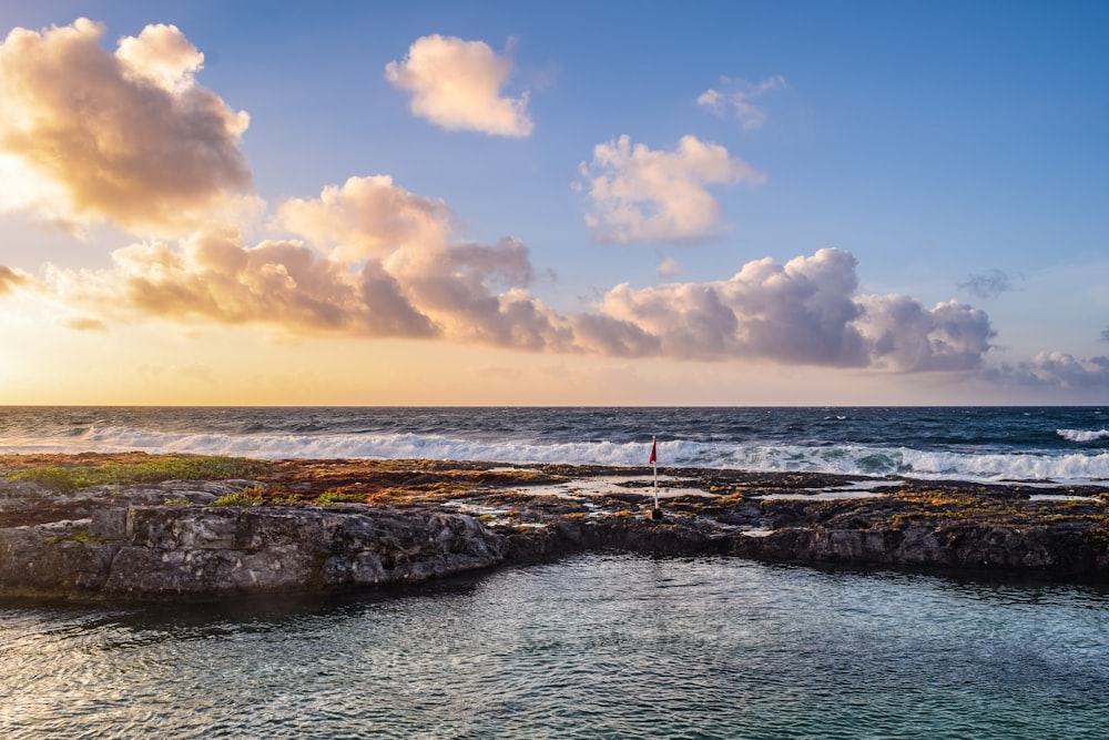 personnes debout sur une formation rocheuse près de la mer pendant la journée