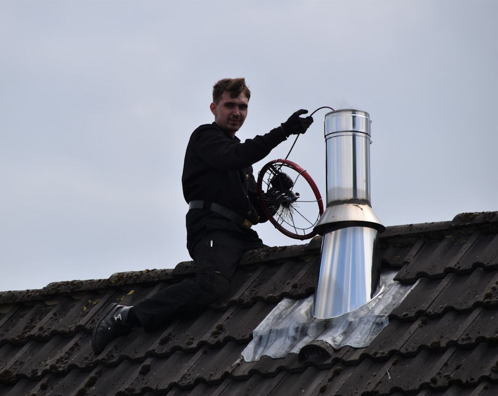 昼間、屋根の上に座る黒いジャケットの男