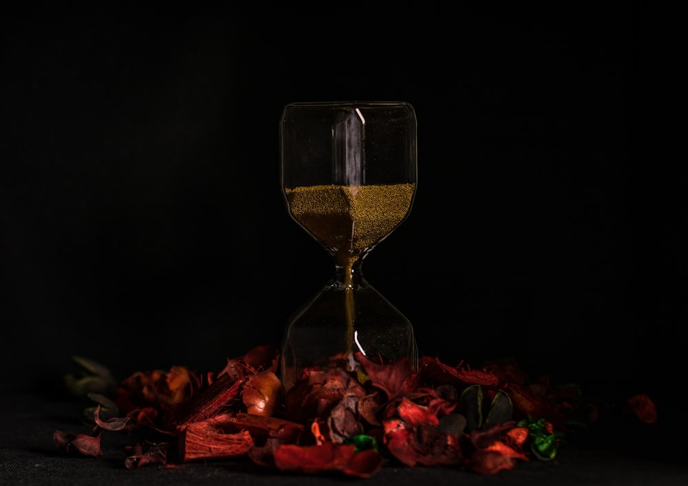 clear glass hour glass on red and yellow leaves