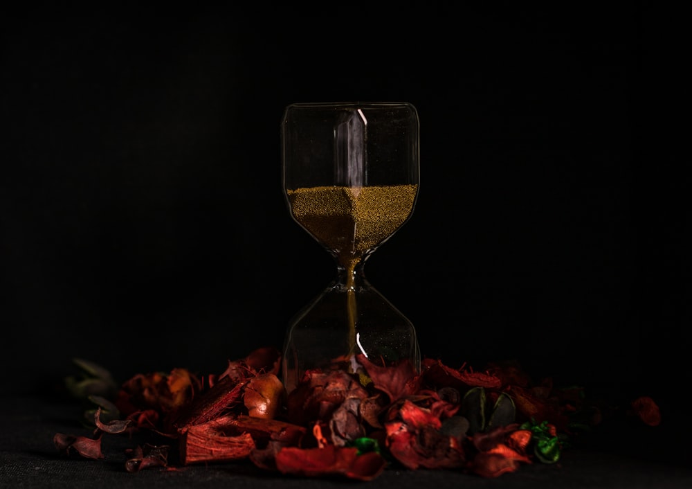 reloj de arena de vidrio transparente sobre hojas rojas y amarillas