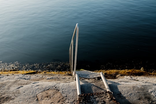 white metal ladder on gray sand near body of water during daytime in Aveiro Portugal