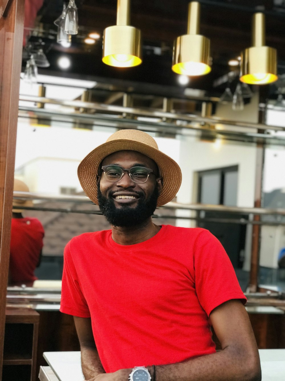 man in red crew neck t-shirt wearing brown fedora hat