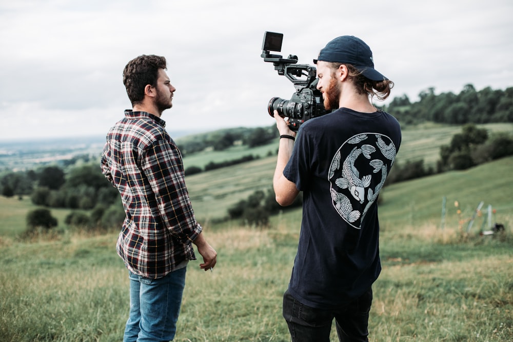 man in black and white crew neck t-shirt holding black video camera