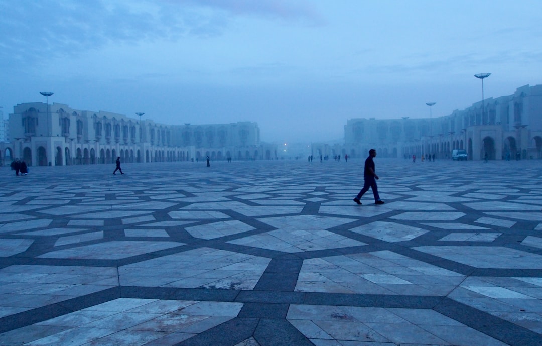 man in black jacket walking on black and white concrete floor during daytime