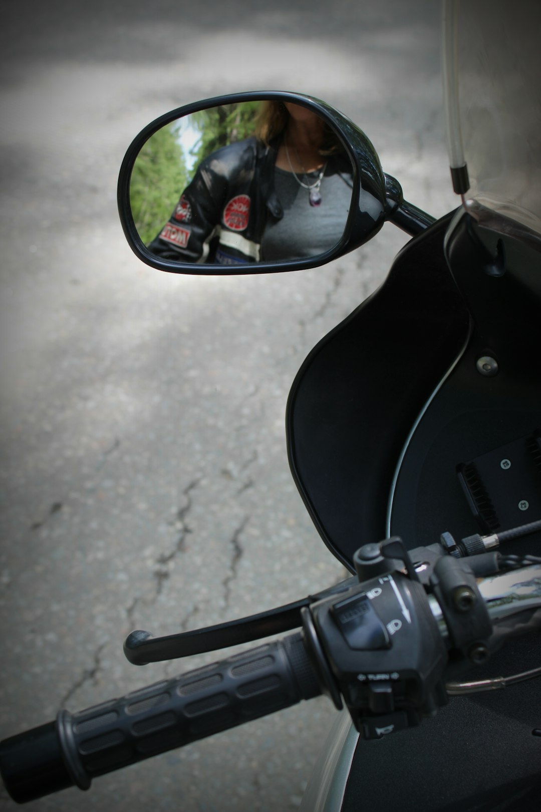 black motorcycle side mirror reflecting man in black sunglasses