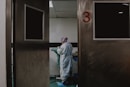 man in white and blue robe standing near white wooden door