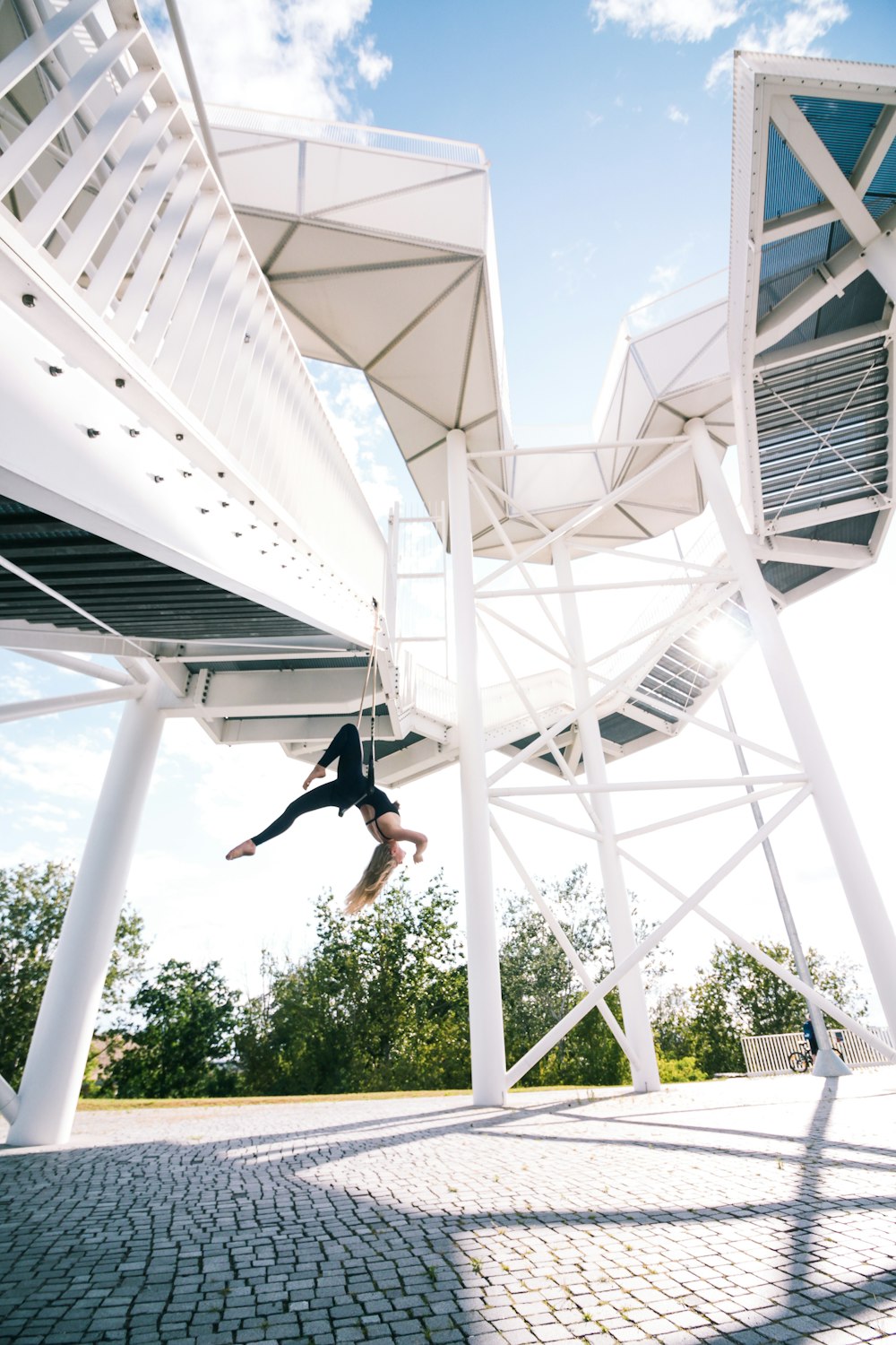 man in black t-shirt and black shorts jumping on white metal frame during daytime