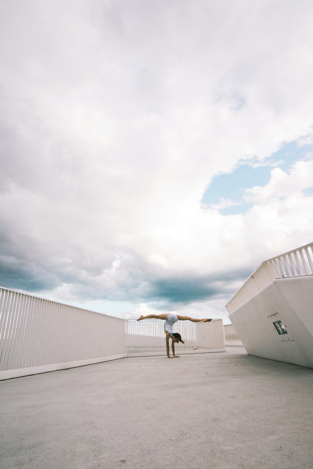 man in black jacket and blue denim jeans standing on white concrete floor under white clouds