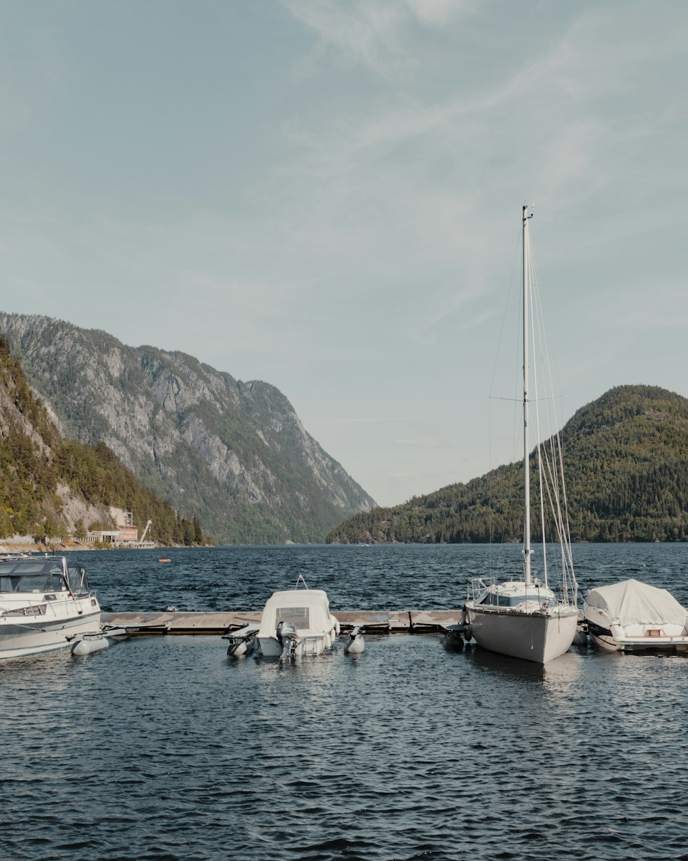 white sail boat on body of water near mountain during daytime