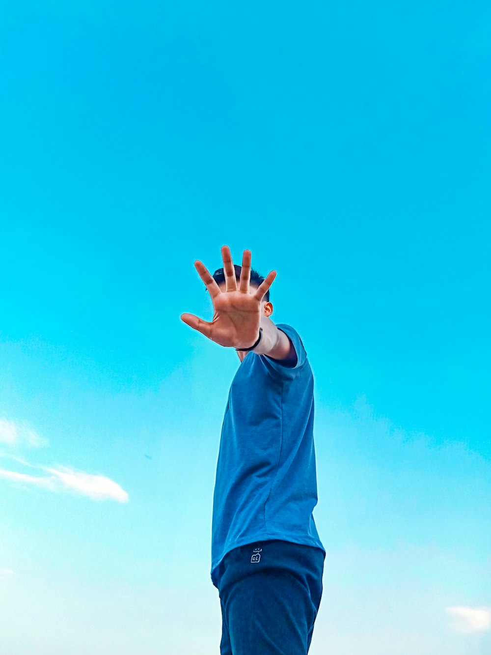 man in blue jacket raising his hands