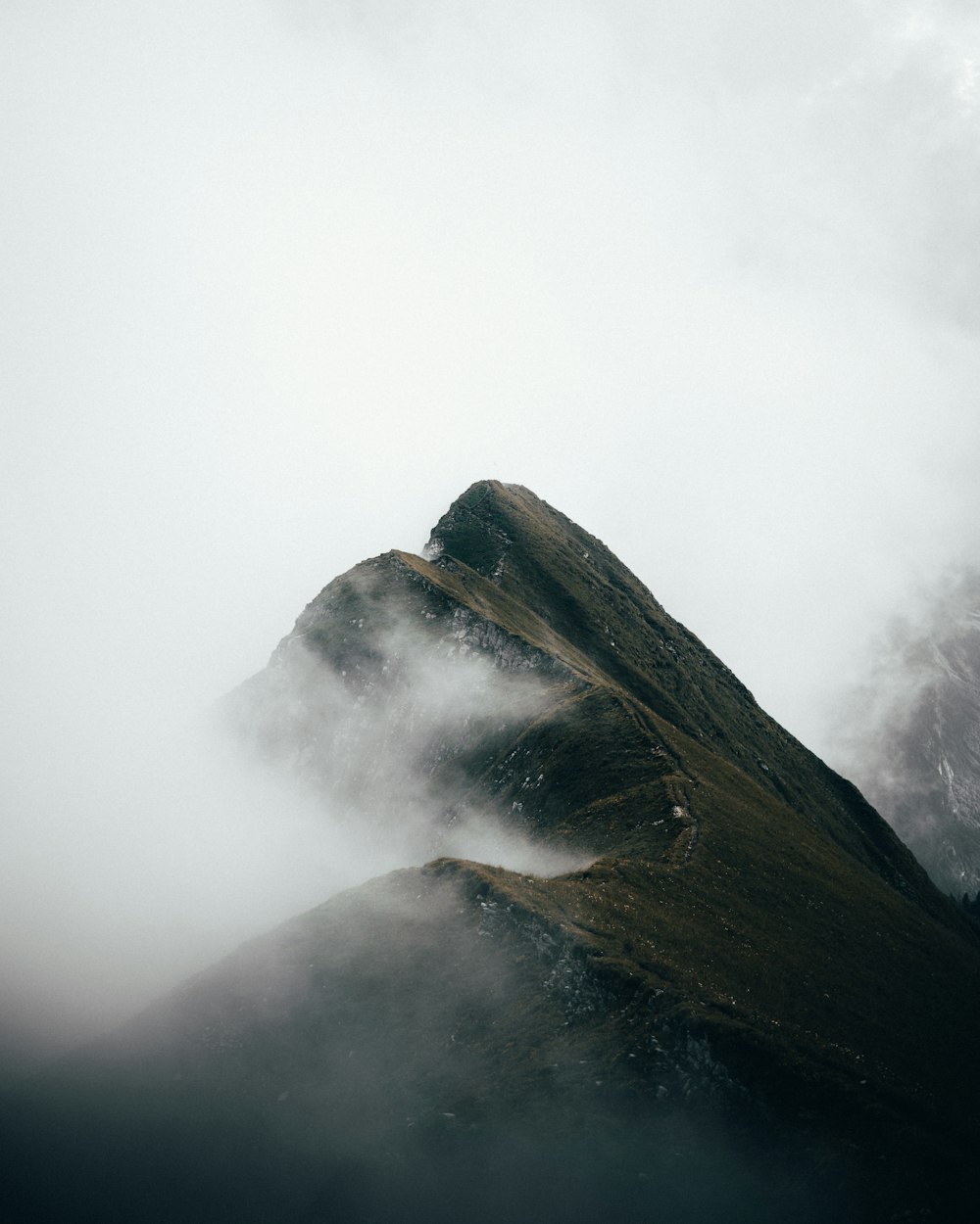 Montaña marrón cubierta de nubes blancas