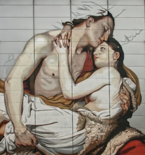 A detailed mural depicting two partially clothed individuals embracing each other tenderly, with one leaning in to kiss the other's forehead. The backdrop includes subtle shading and coloring, enhancing the emotional depth of the scene.