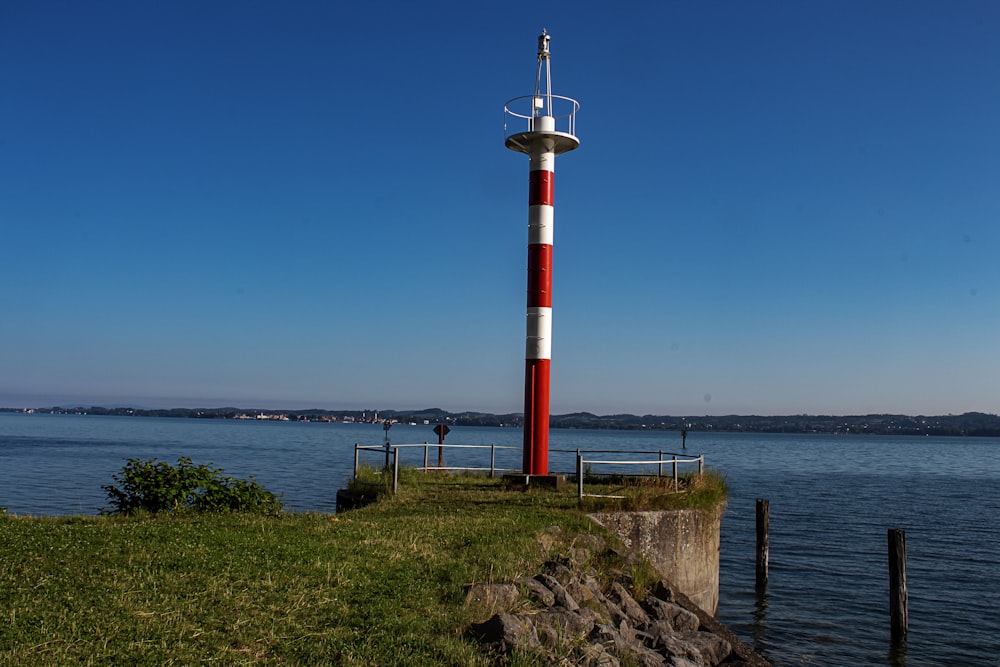 white and red lighthouse near body of water during daytime