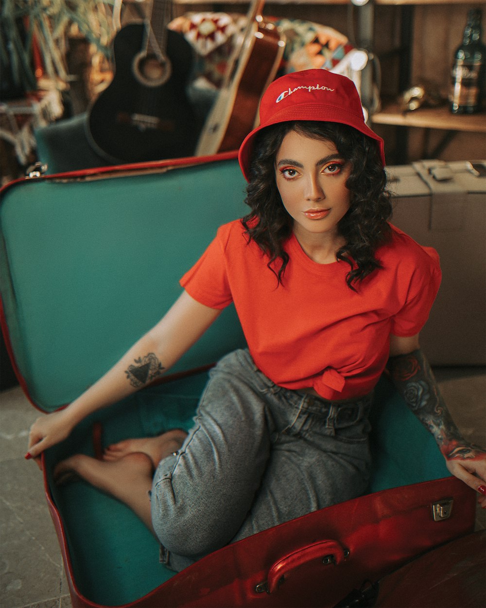 woman in red crew neck t-shirt and blue denim jeans sitting on red chair