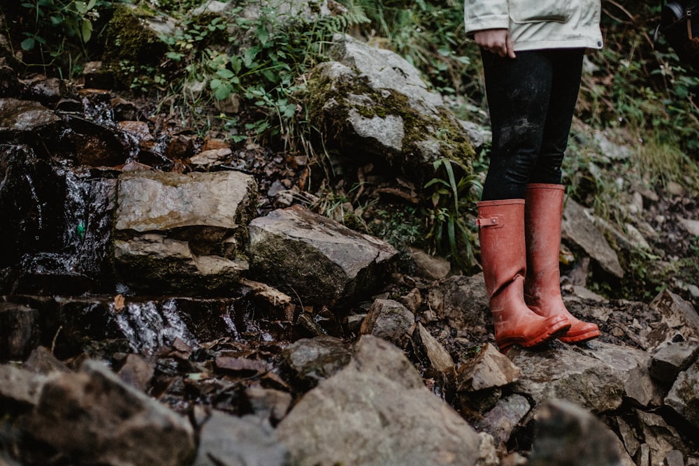 person in red leather boots standing on rocky ground