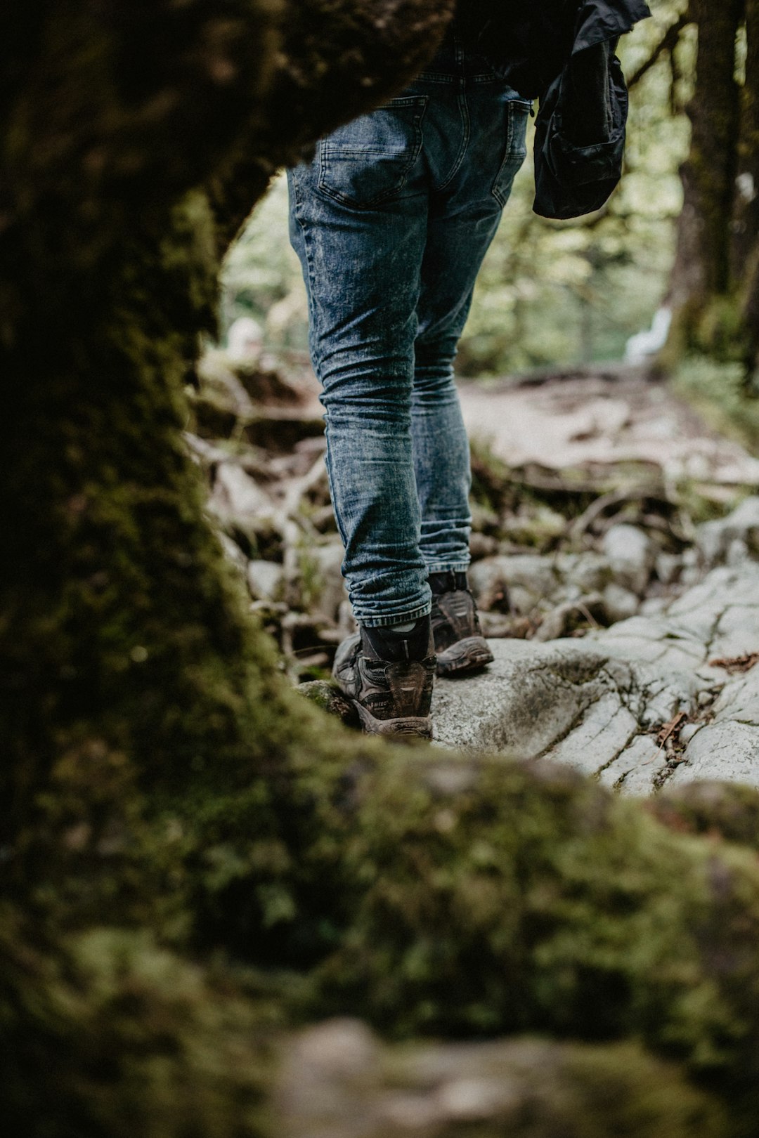 person in blue denim jeans standing on rocky road during daytime