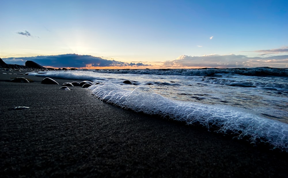 ocean waves crashing on shore during sunset