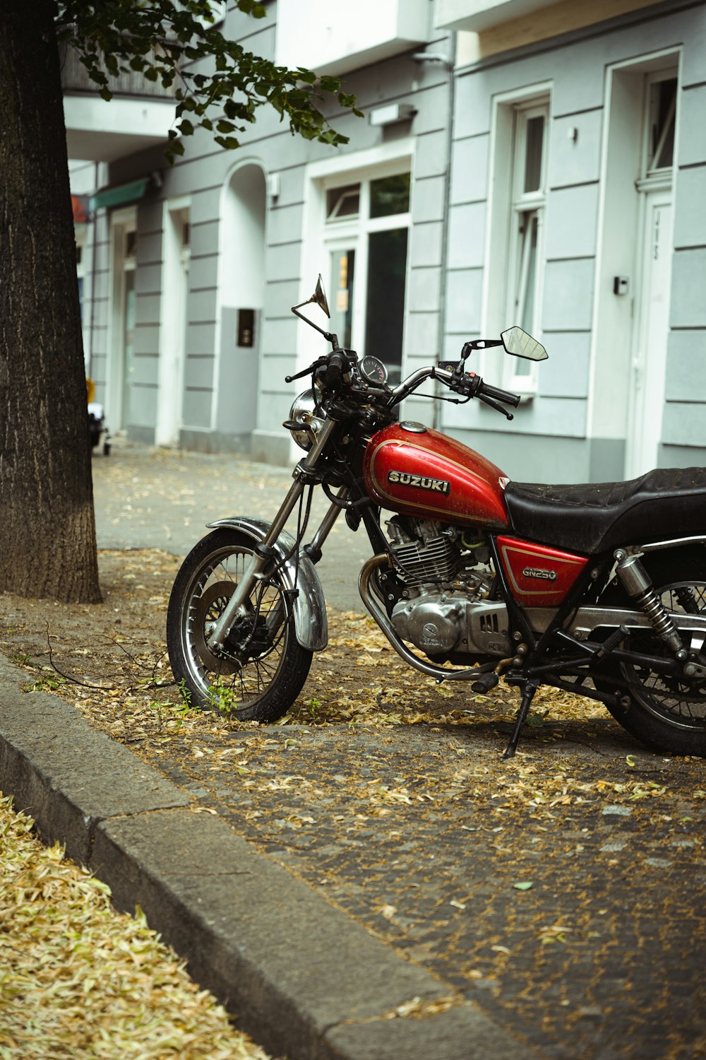 Motocicleta estándar roja y negra estacionada junto a la puerta de madera blanca