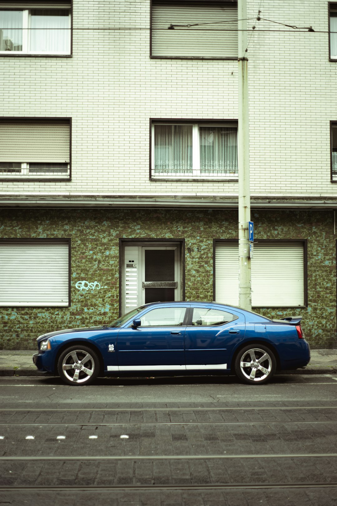 blue coupe parked beside white building