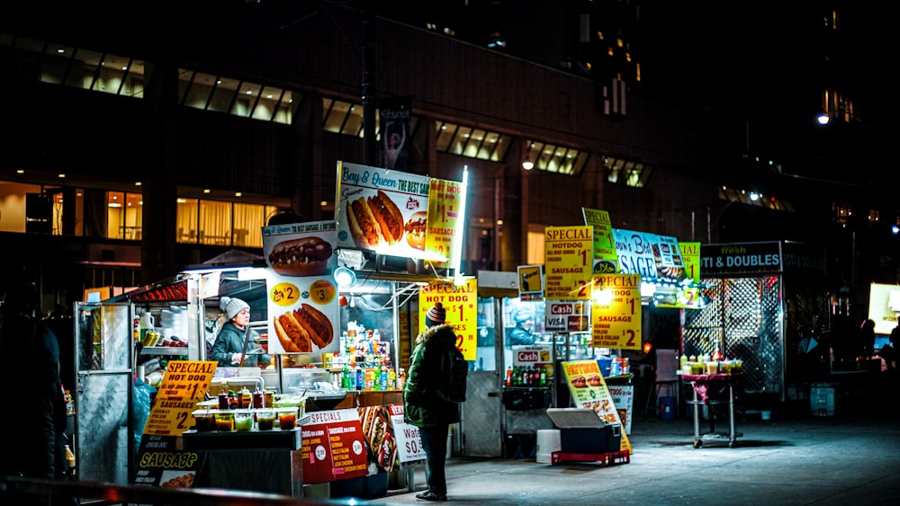 man in black jacket standing in front of store during nighttime