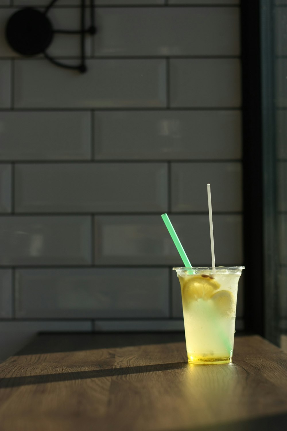 Bicchiere trasparente con liquido giallo e cannuccia verde