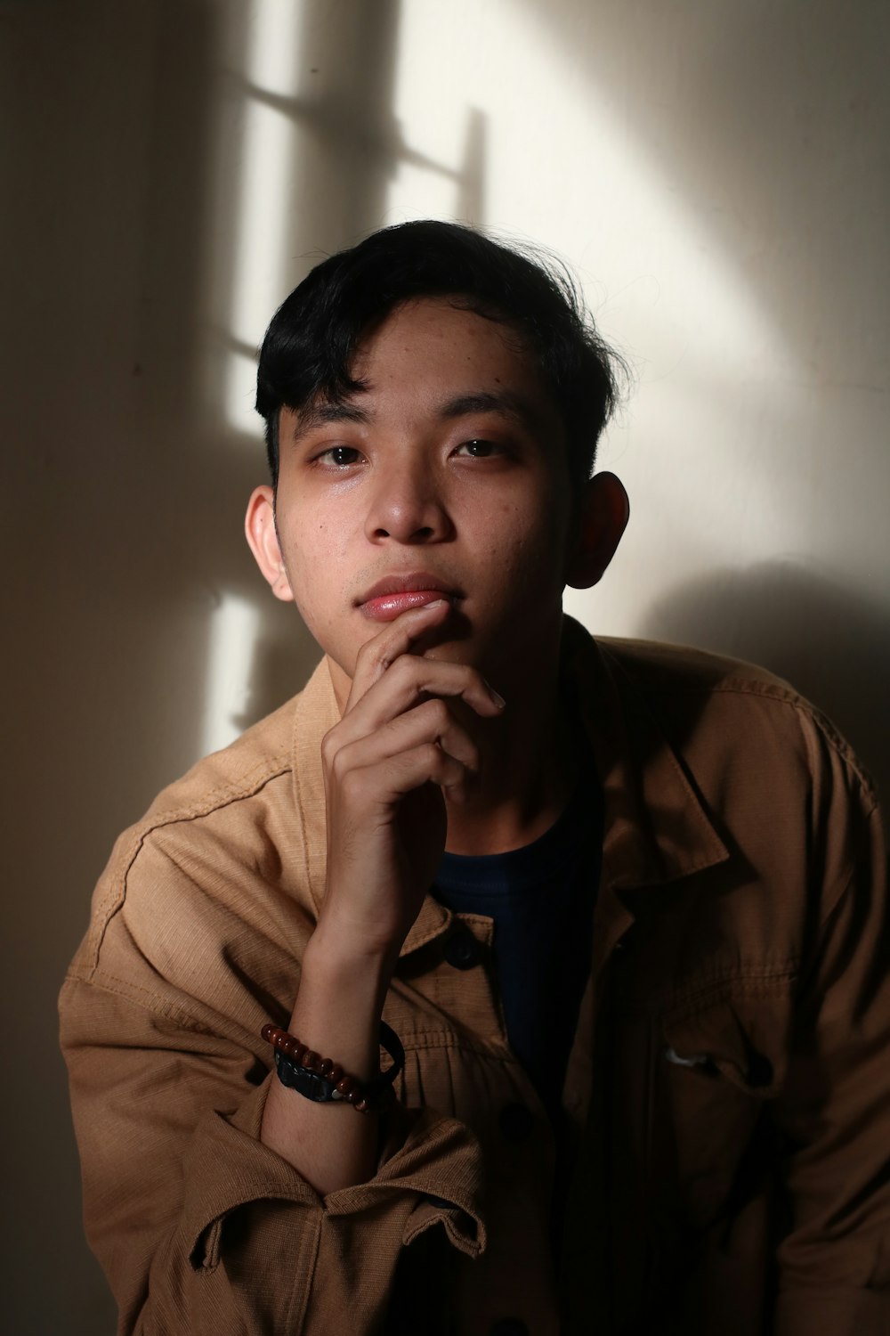 a young man poses for a picture with his hands on his chin