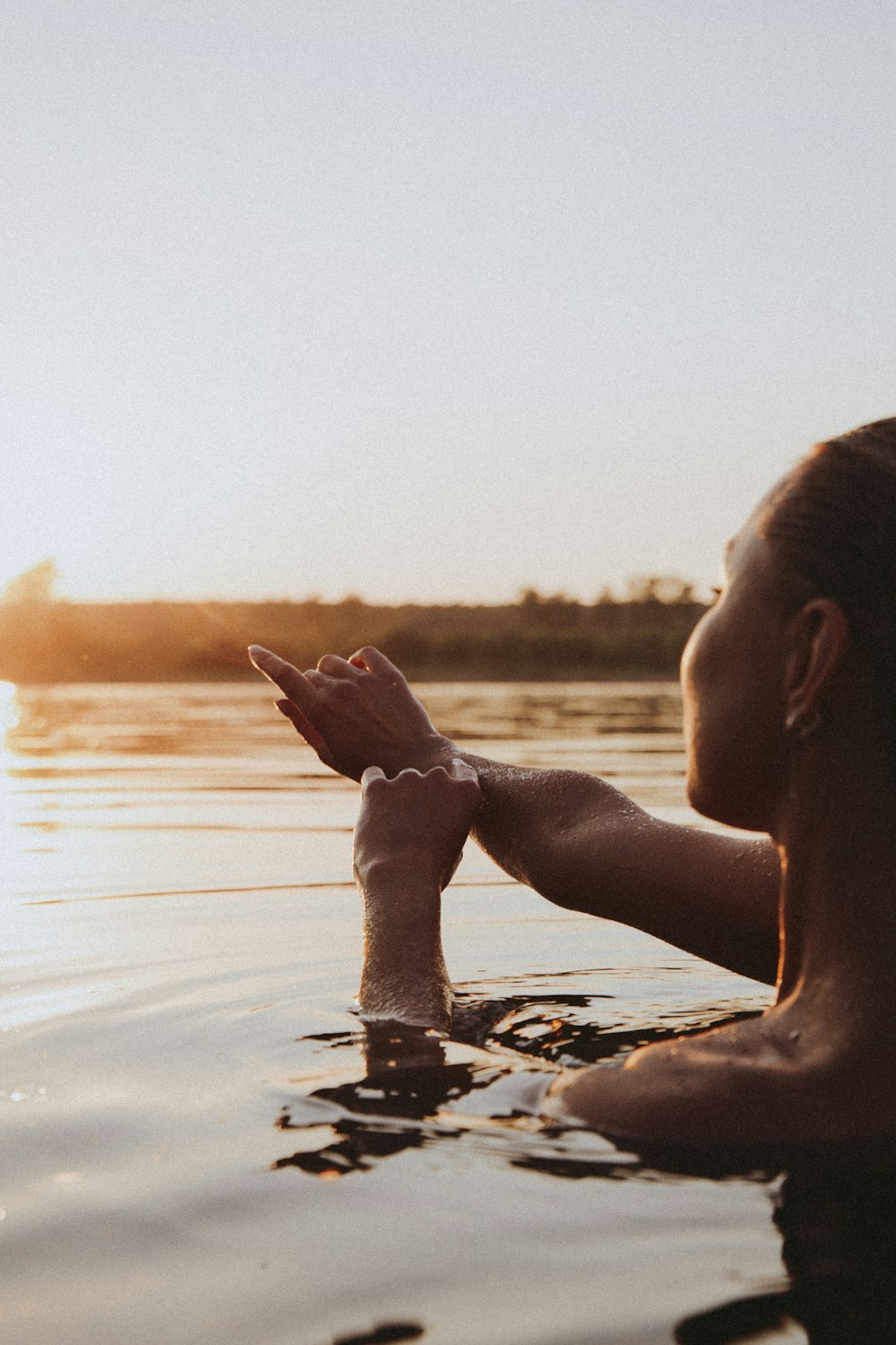 chico en topless en el agua durante la puesta del sol