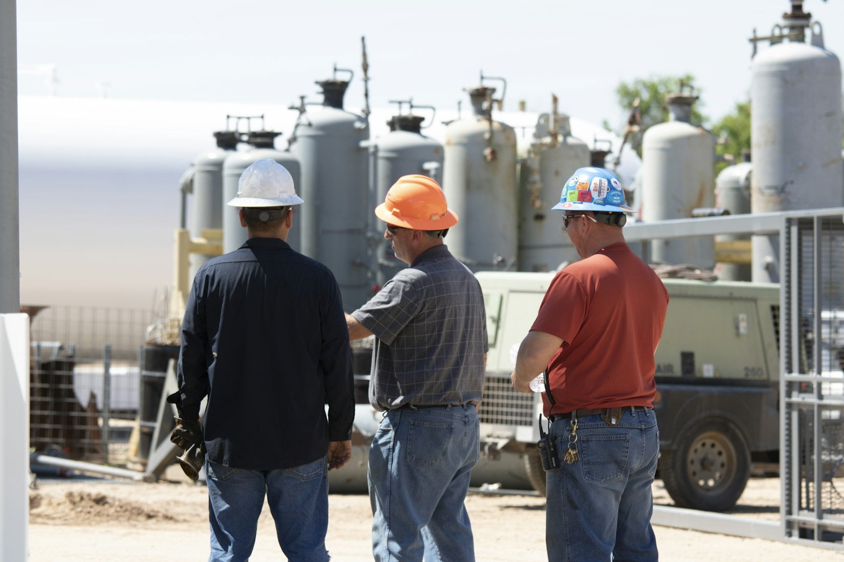 Three men discussing equipment wearing hard hats in Houston, Texas (Christina Hawkins via Unsplash)