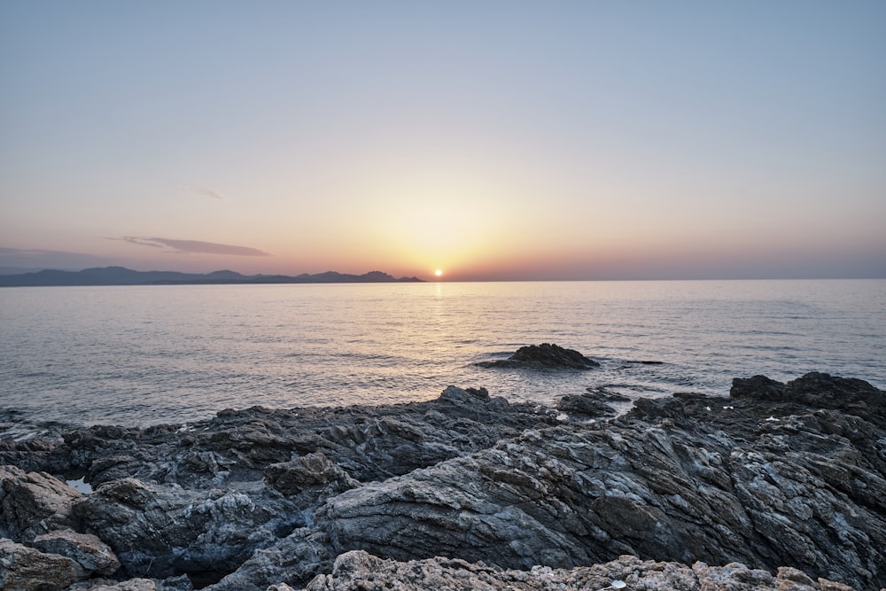 black rock formation near sea during sunset