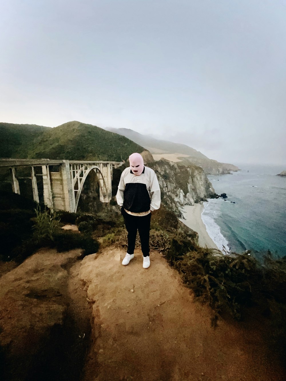 woman in white jacket standing on brown bridge during daytime