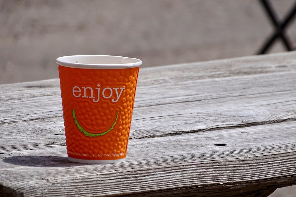 orange and white disposable cup on brown wooden table