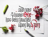 Close-up of a delicate handmade calligraphy piece featuring flowing script in black ink on textured white paper.