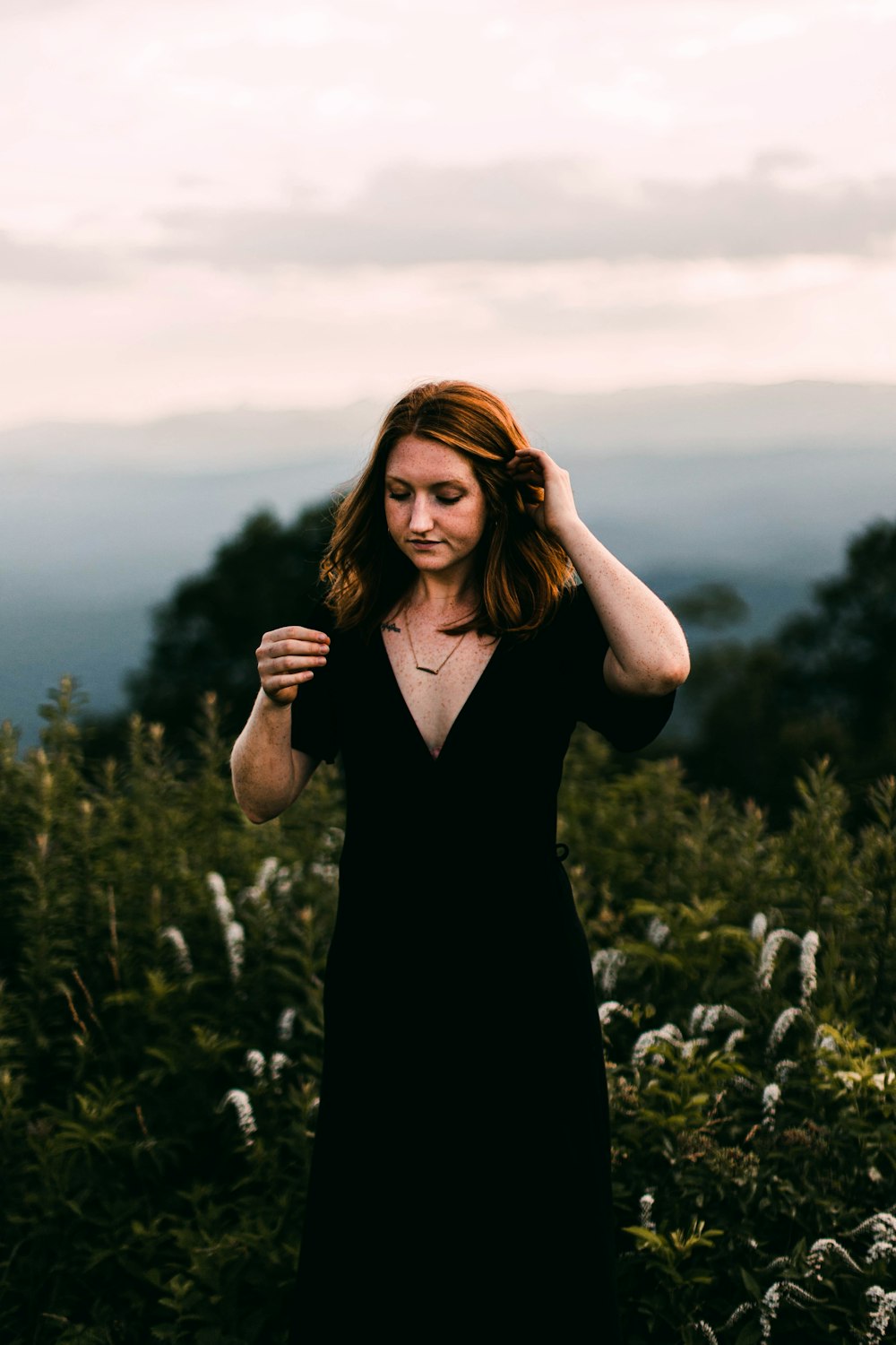 woman in black dress standing on green grass field during daytime