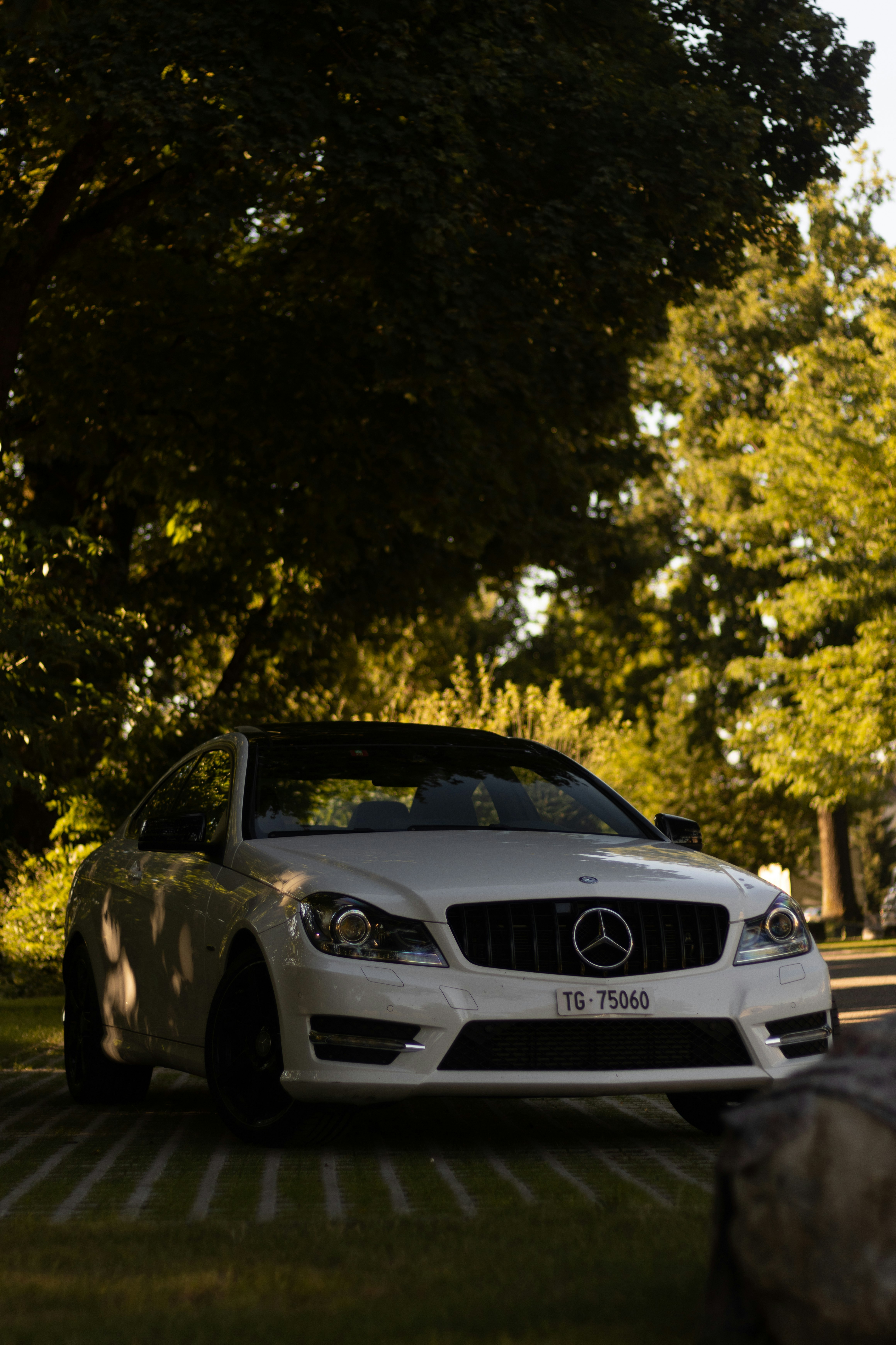 black mercedes benz c class parked near green trees during daytime