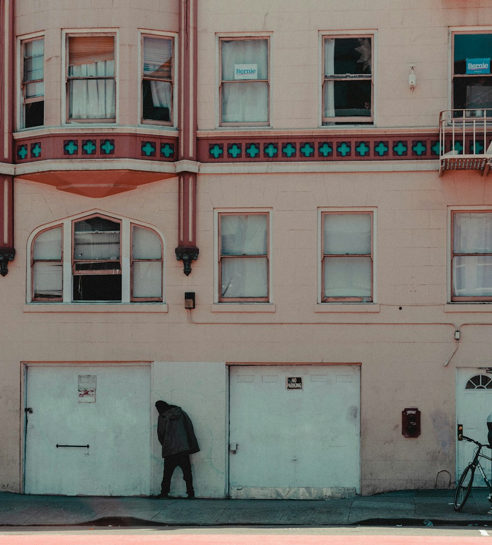 man in black jacket walking on sidewalk near red building during daytime