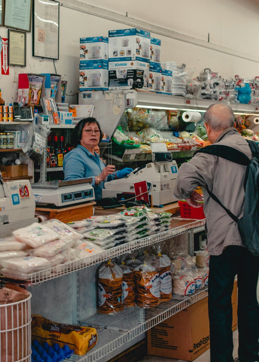 man in black jacket standing in front of food display counter